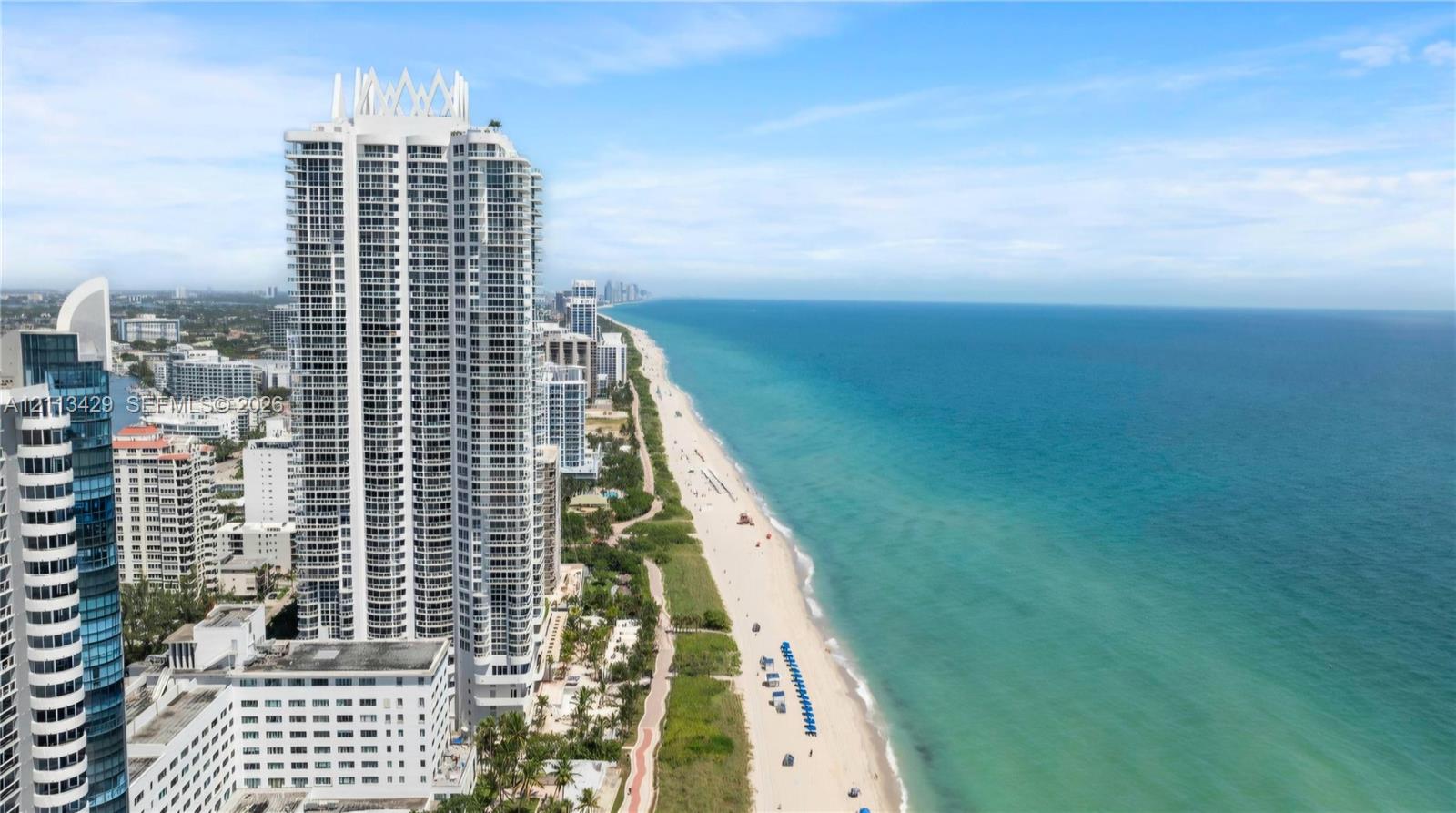 High-rise tower featuring a tiered architectural design and direct frontage on a sandy coastline