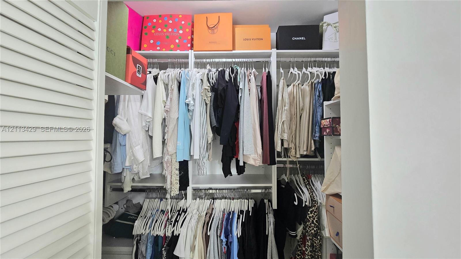 Custom closet organization system featuring white laminate shelving, adjustable vertical supports, and dual-level hanging rods