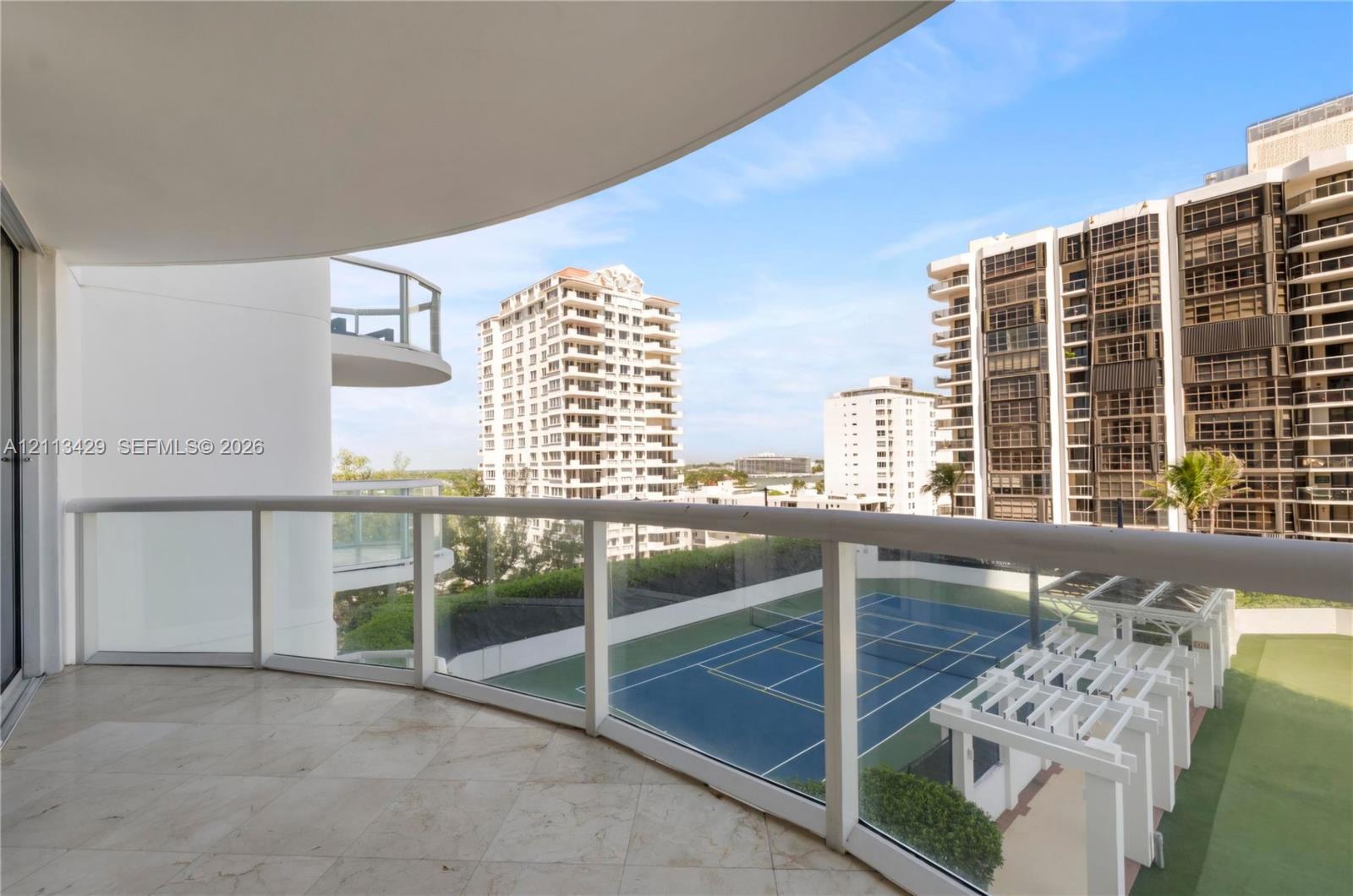 Covered balcony featuring stone flooring and a glass-paneled railing