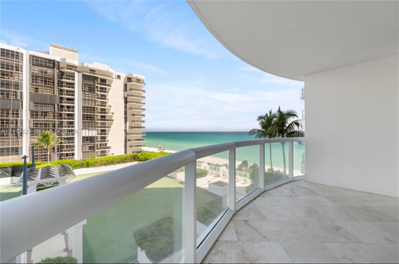 Covered balcony featuring stone-tile flooring and a glass-paneled railing with a rounded metal top rail
