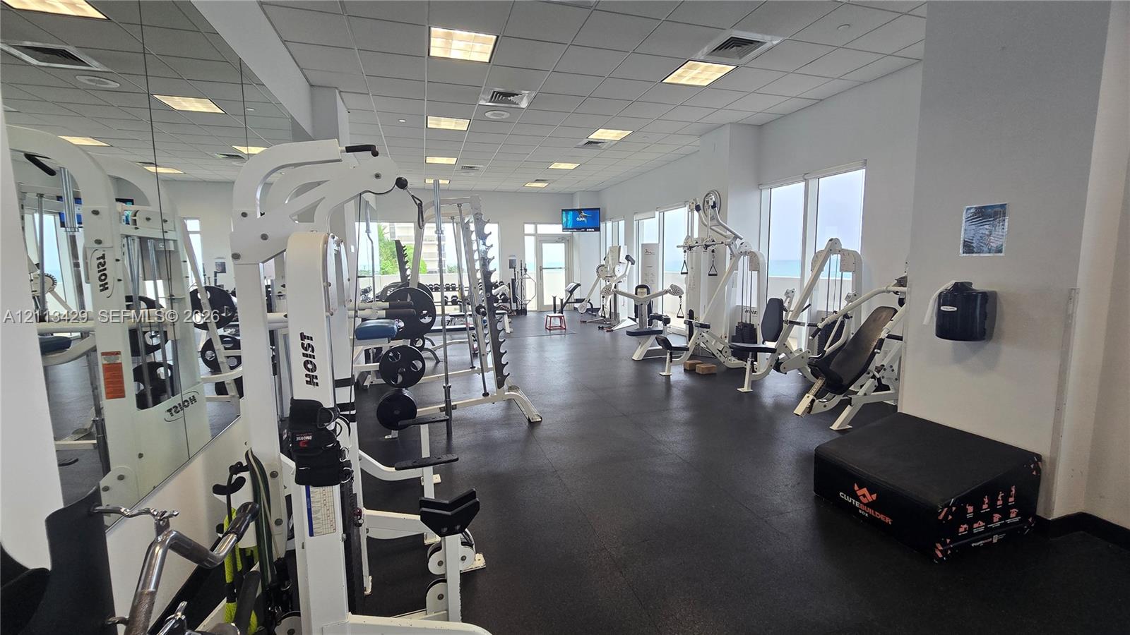 Fitness center featuring rubber flooring, expansive wall-to-wall mirrors, recessed lighting, and large windows