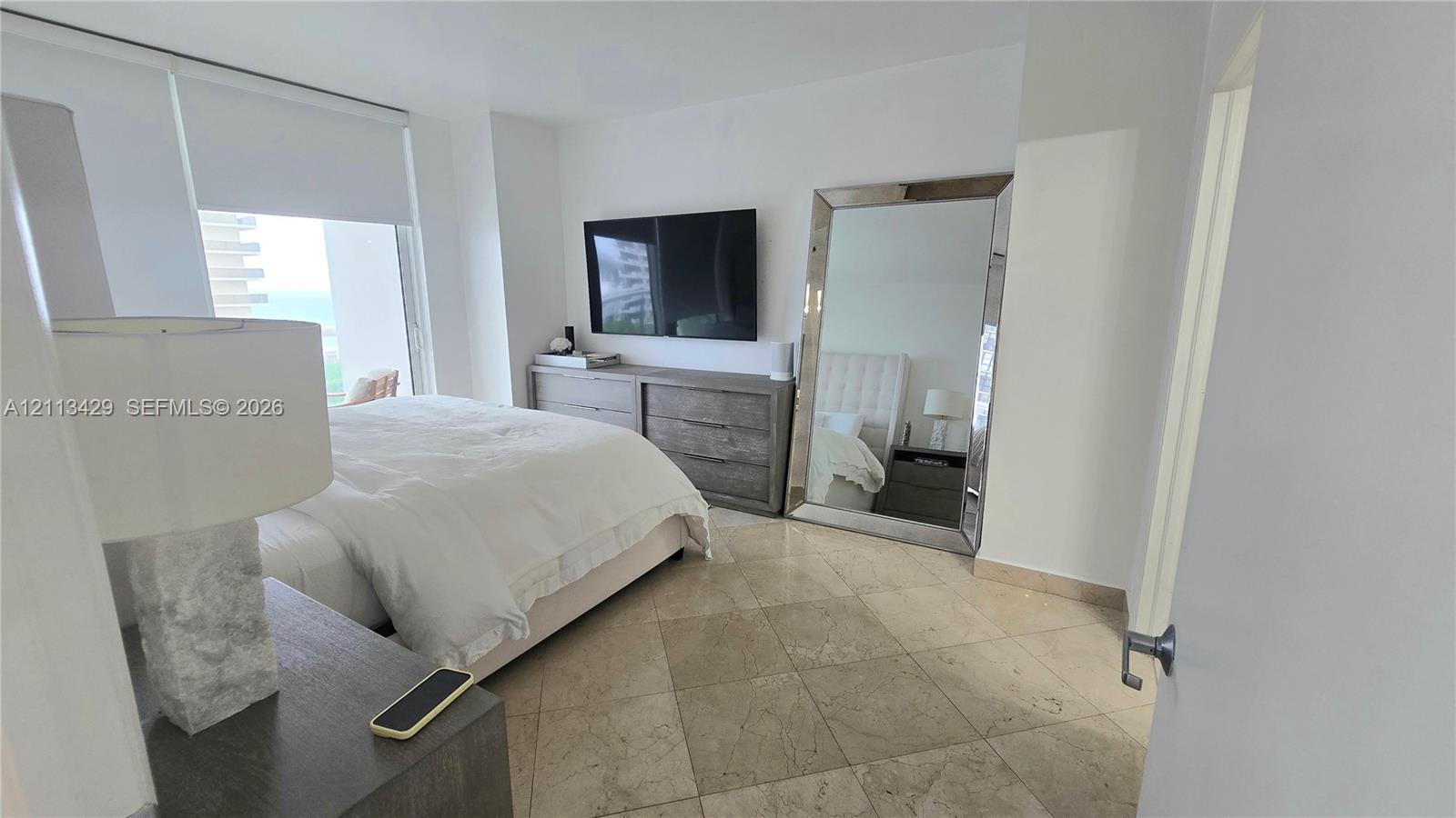 Natural stone tile flooring, floor-to-ceiling window, and neutral wall palette