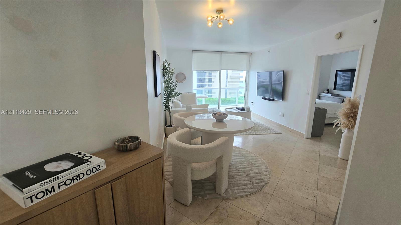 Large-format tile flooring, multi-arm ceiling fixture, and sliding glass balcony doors