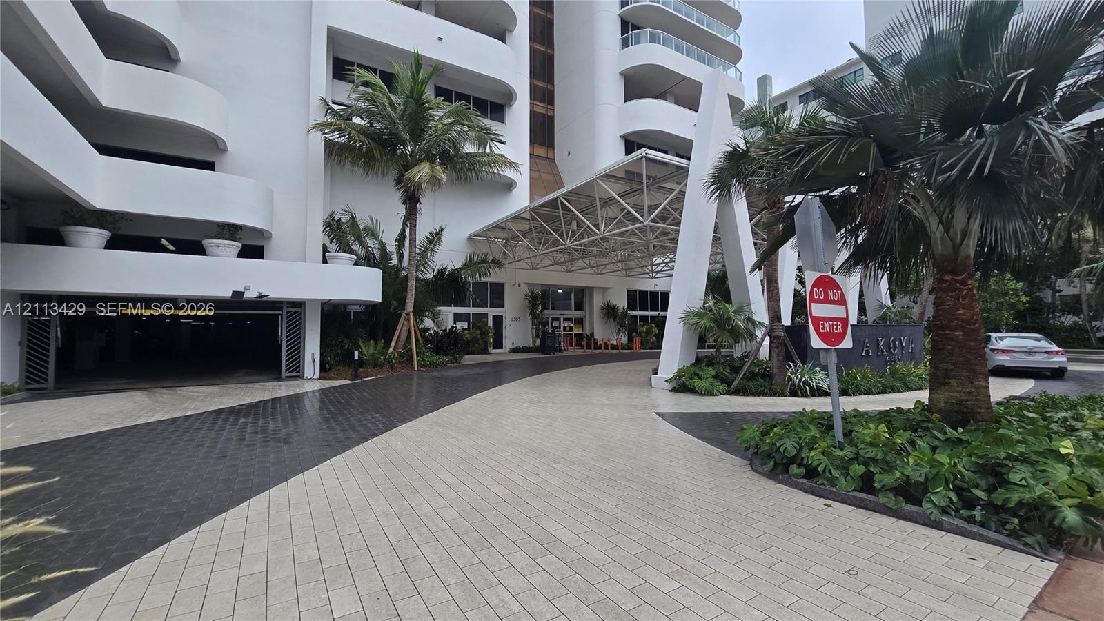 Building exterior featuring a geometric porte-cochre, paved circular motor court, and covered parking entrance