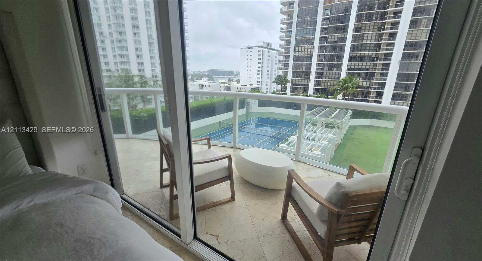 Private balcony featuring stone tile flooring and a glass panel railing
