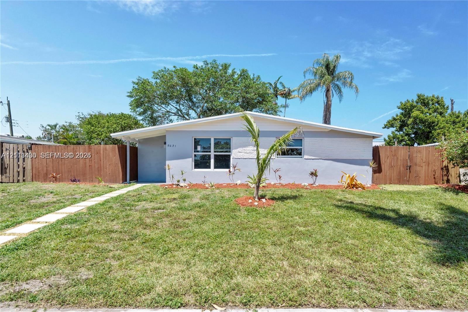 Single-story residence featuring a painted masonry exterior, low-pitch roofline, horizontal wood fencing, and a concrete paver walkway Single-story residence featuring a painted masonry exterior, low-pitch roofline, horizontal wood fencing, and a concrete paver walkway