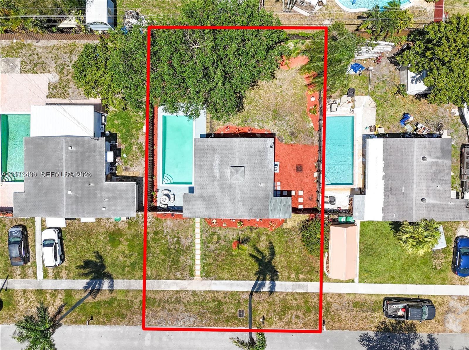 Aerial perspective of property featuring an in-ground swimming pool, concrete patio, mature trees, and perimeter fencing Aerial perspective of property featuring an in-ground swimming pool, concrete patio, mature trees, and perimeter fencing