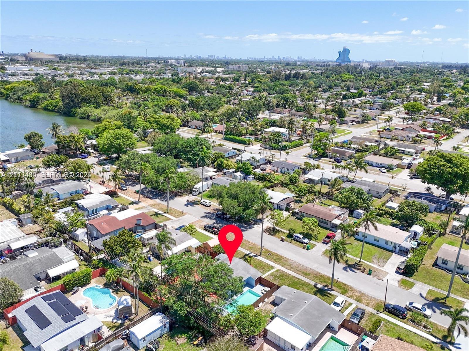 Aerial view of the residential property featuring an in-ground swimming pool, privacy fencing, mature trees, and proximity to the canal Aerial view of the residential property featuring an in-ground swimming pool, privacy fencing, mature trees, and proximity to the canal