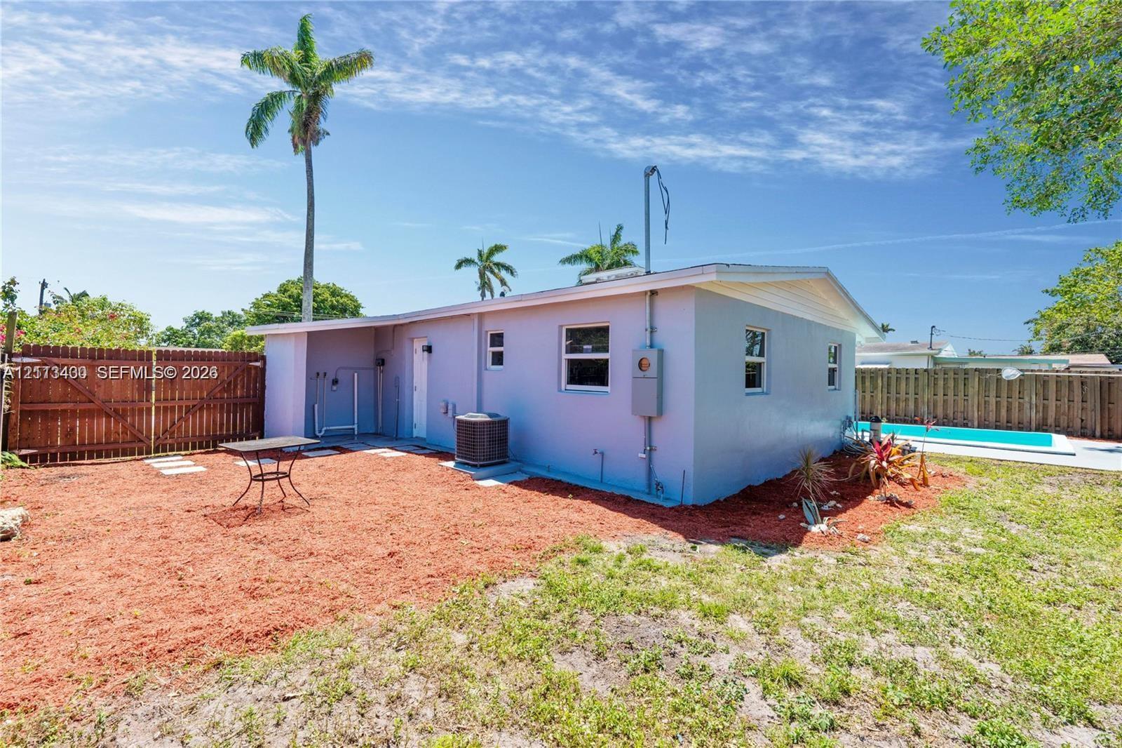 Rear exterior featuring a stucco facade, wood-plank privacy fencing, and an in-ground swimming pool