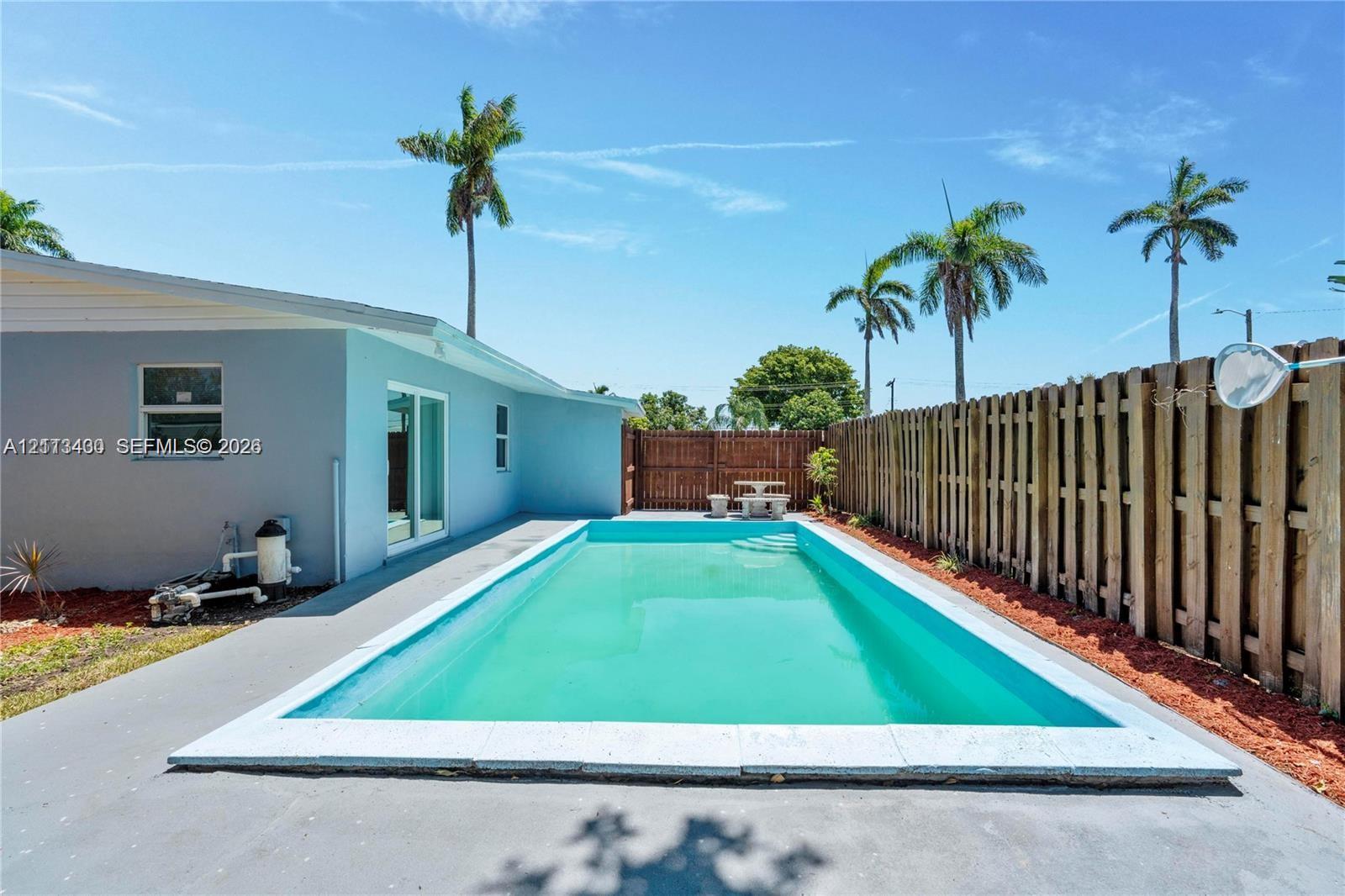 In-ground swimming pool with concrete decking, enclosed by a full-height wood privacy fence In-ground swimming pool with concrete decking, enclosed by a full-height wood privacy fence