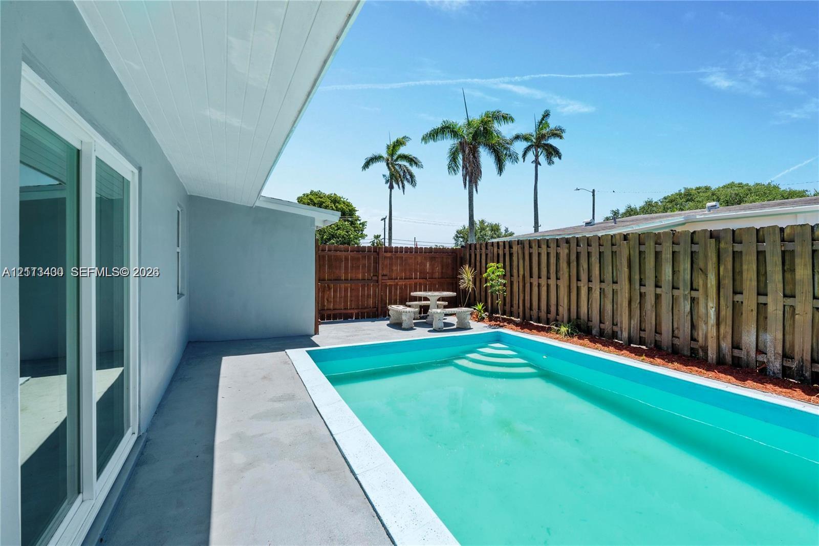 Private backyard featuring a concrete pool deck, in-ground swimming pool with integrated steps, and wood privacy fencing