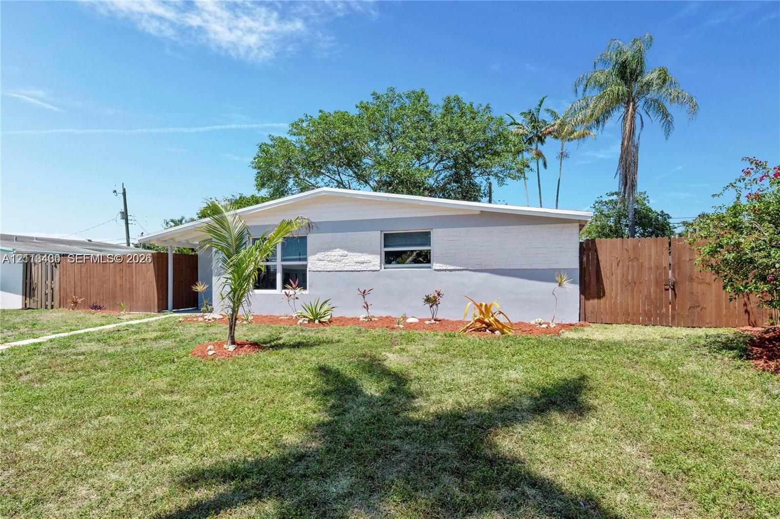 Single-story exterior featuring a two-tone painted facade, horizontal sliding windows, a covered entryway, and wood-panel fencing Single-story exterior featuring a two-tone painted facade, horizontal sliding windows, a covered entryway, and wood-panel fencing