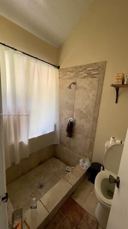 Walk-in shower enclosure featuring tiled flooring, natural-tone wall tile surround, decorative mosaic accent trim, and wall-mounted shower fixture