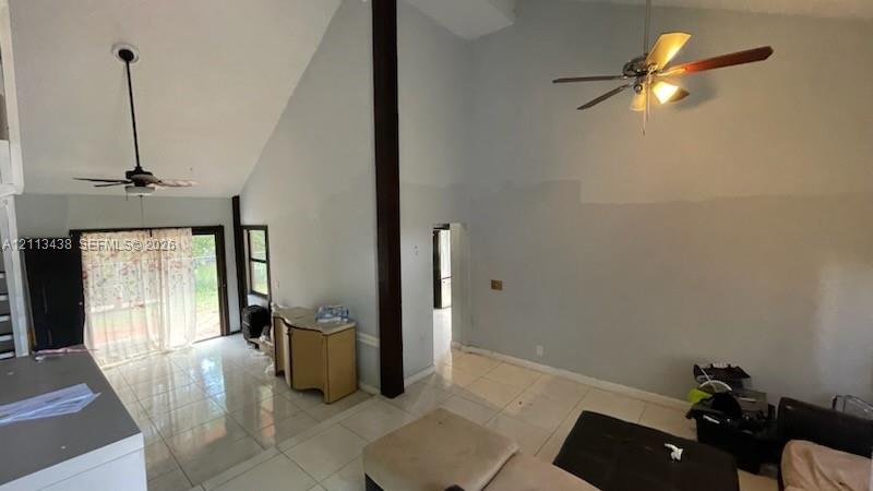 Vaulted ceilings, exposed vertical support beam, ceramic tile flooring, and dual ceiling fans