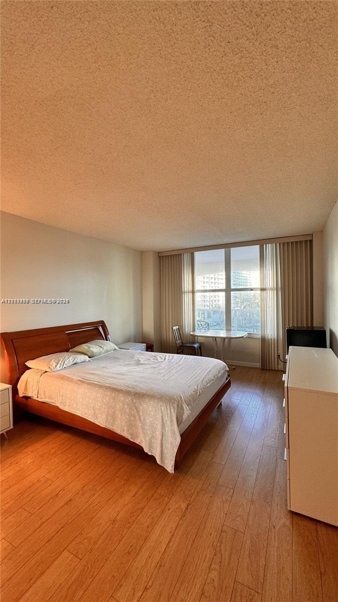 Wood-finish flooring, floor-to-ceiling windows, and vertical blinds