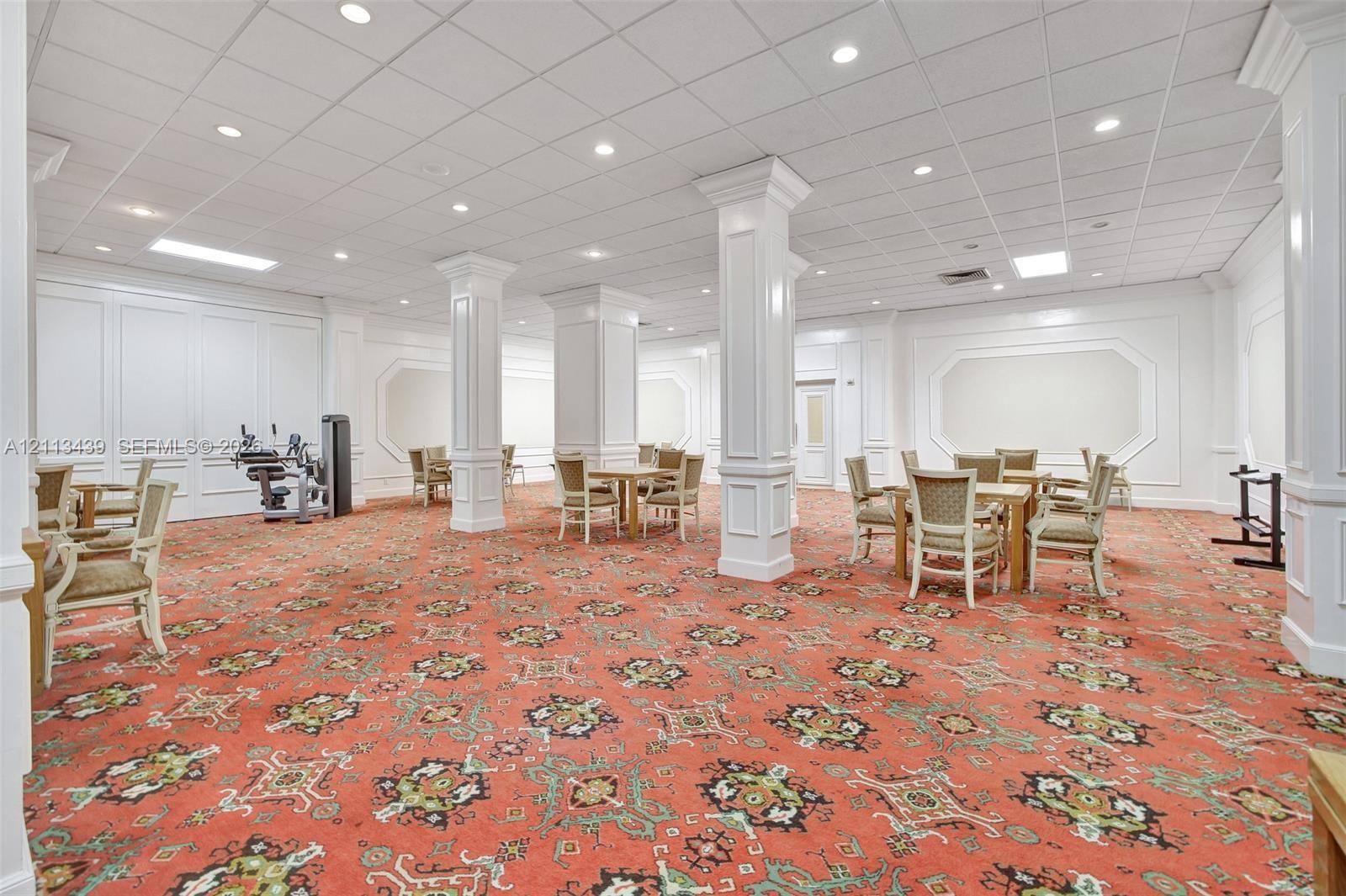 Open-concept interior featuring structural columns with wainscoting detail, wall molding, recessed lighting, and a drop ceiling