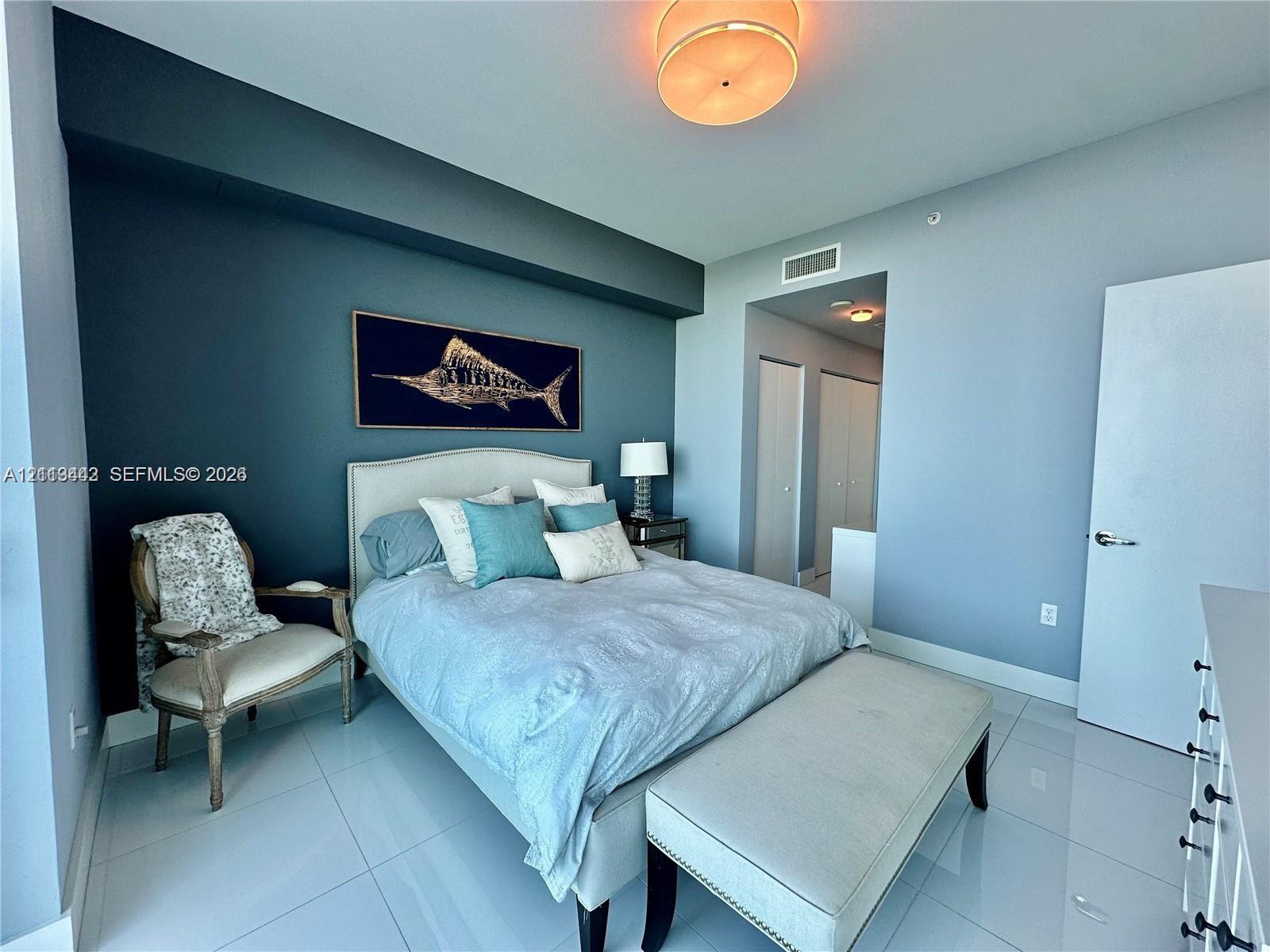 Bedroom featuring smooth-finish tile flooring, a deep-toned accent wall, and a recessed ceiling lighting fixture