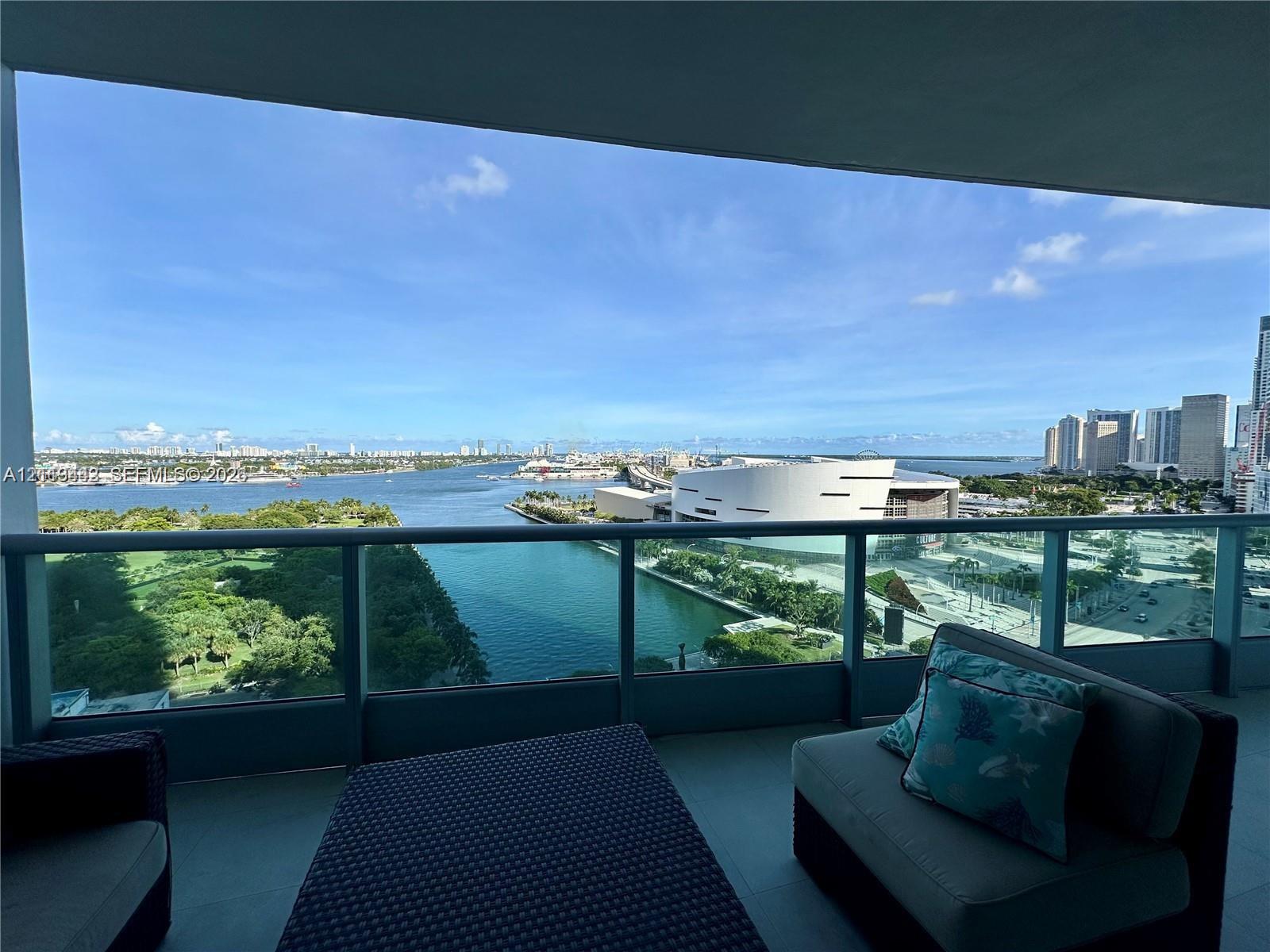 Covered balcony with a glass and metal railing, concrete flooring, and water frontage