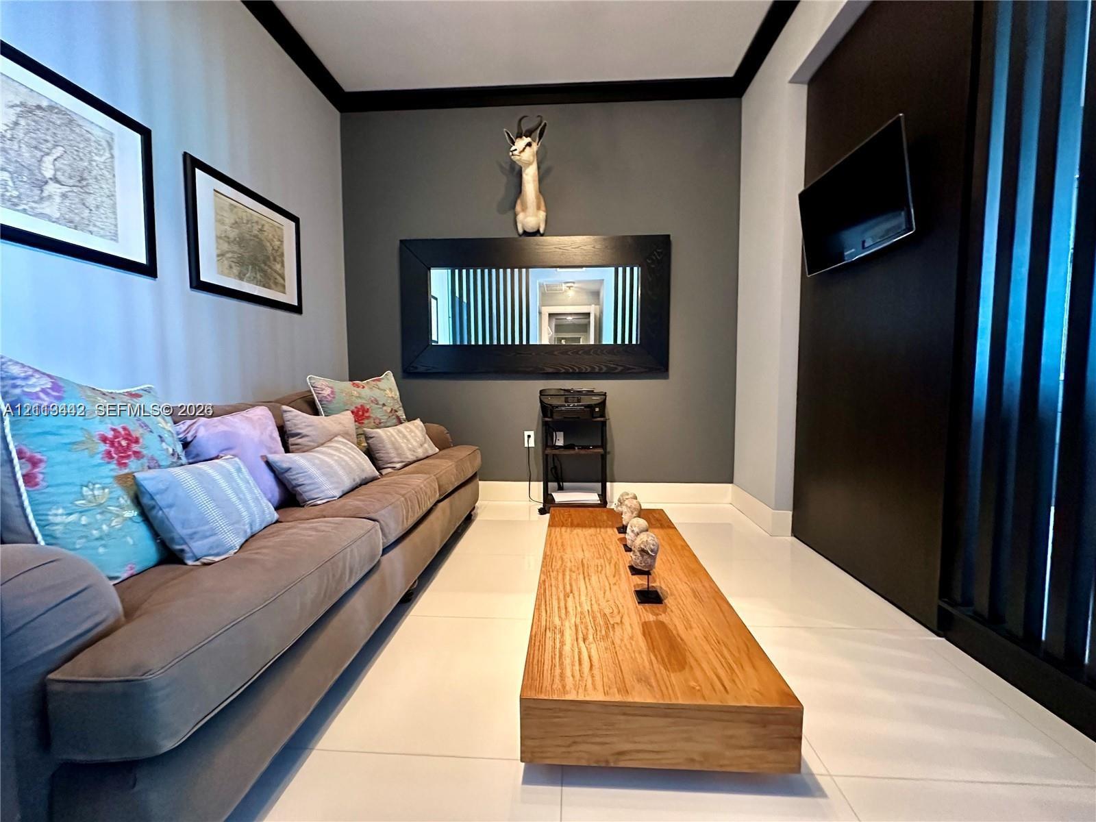 Interior space featuring large-format tile flooring, high-contrast dark accent walls, a built-in horizontal black-framed mirror, and vertical slat wood-finish partition wall
