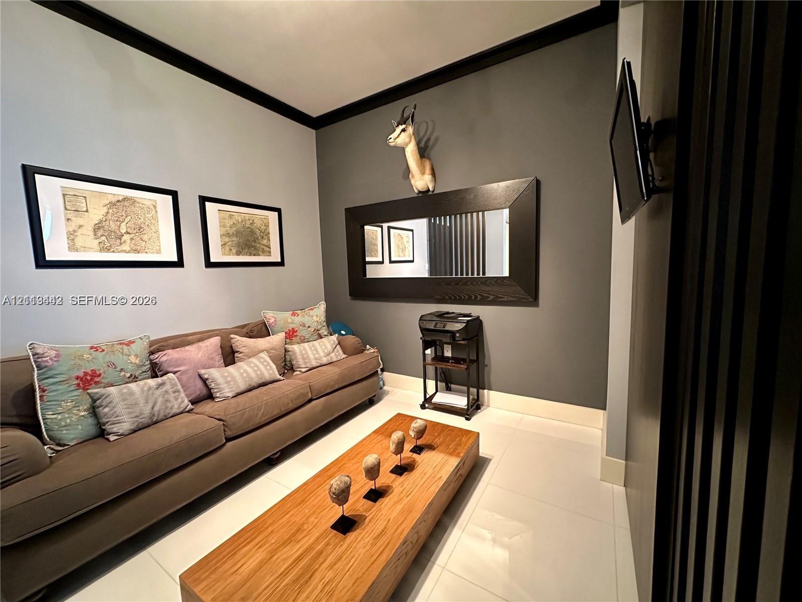 Interior space featuring large-format light-toned flooring, high-contrast dark crown molding, and a prominent decorative wall-mounted mirror