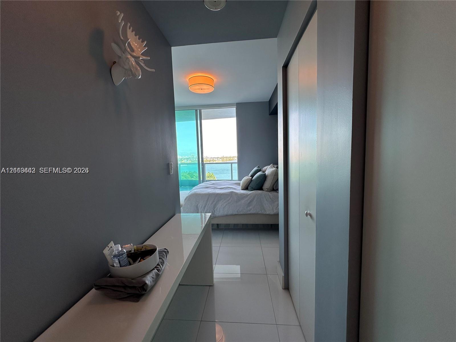 Hallway featuring large-format tile flooring, a built-in wall-mounted console, and floor-to-ceiling sliding glass doors