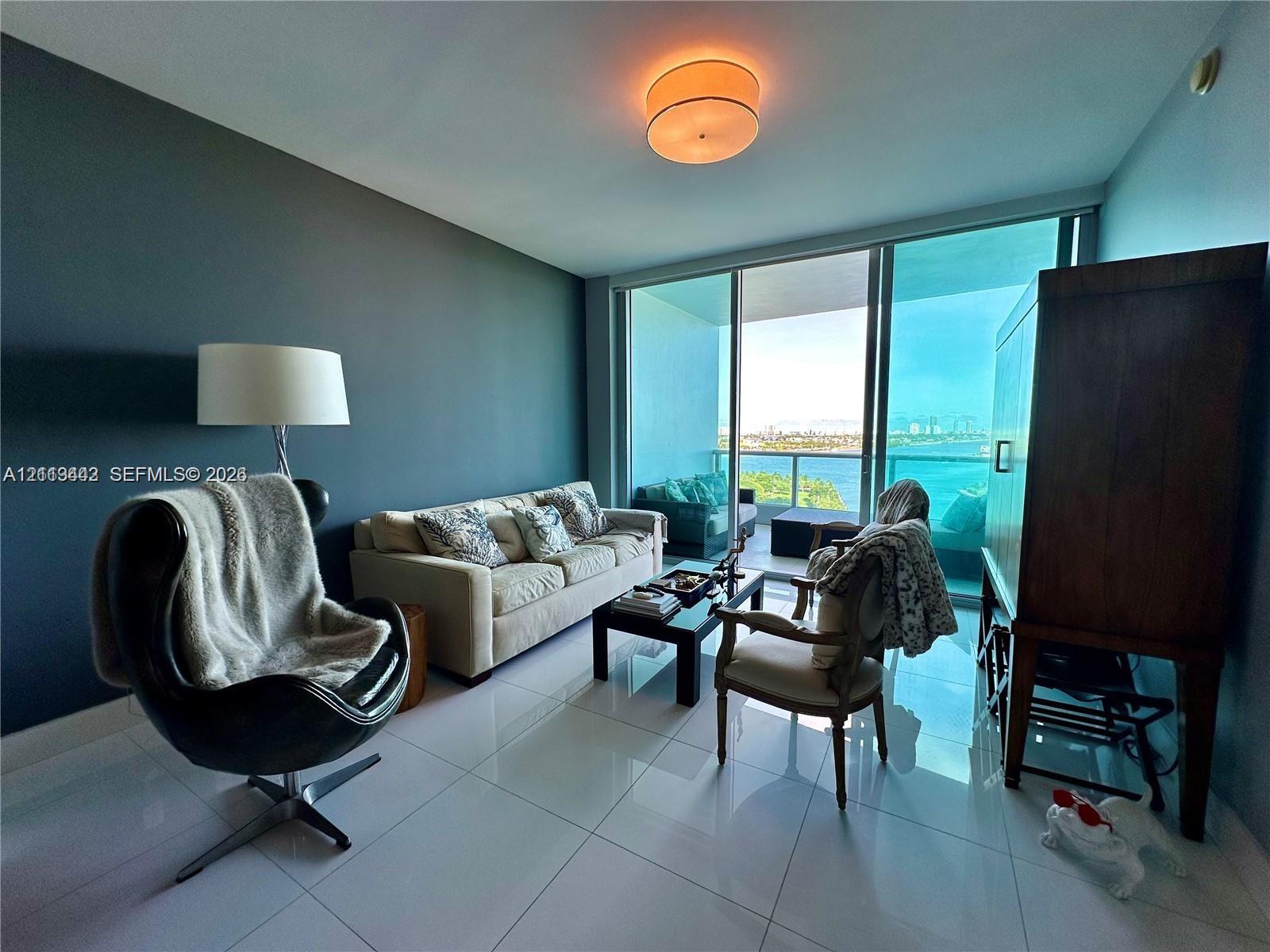 Living area featuring large-format tile flooring, floor-to-ceiling glass sliding doors, and a neutral-toned ceiling light fixture