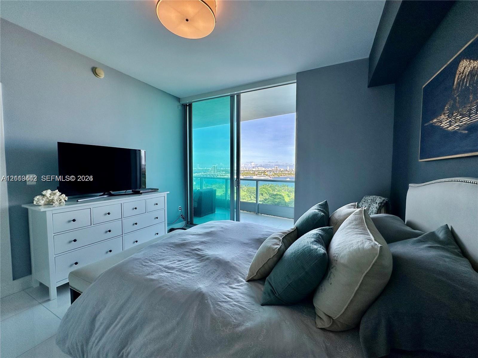 Floor-to-ceiling glass sliding doors, private balcony, large-format tile flooring, and round flush-mount ceiling lighting