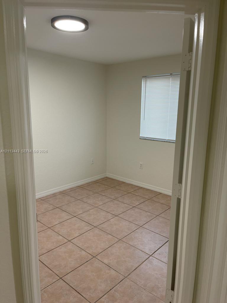 Neutral-toned walls, tile flooring, flush-mount ceiling lighting, and window with horizontal blinds