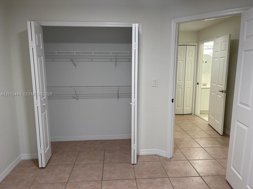 Closet featuring bi-fold doors and dual-tier wire shelving, finished with ceramic tile flooring