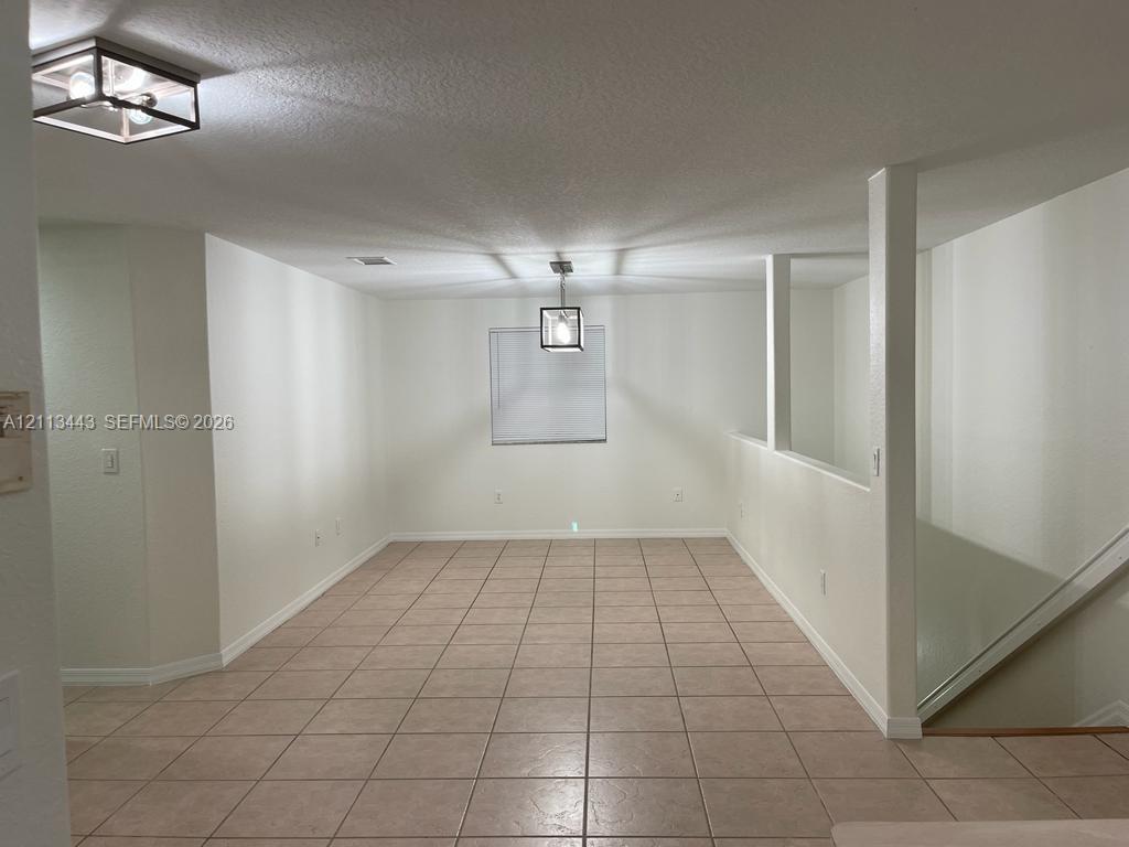 Neutral tile flooring, dual geometric glass-paneled light fixtures, and structural half-wall detailing