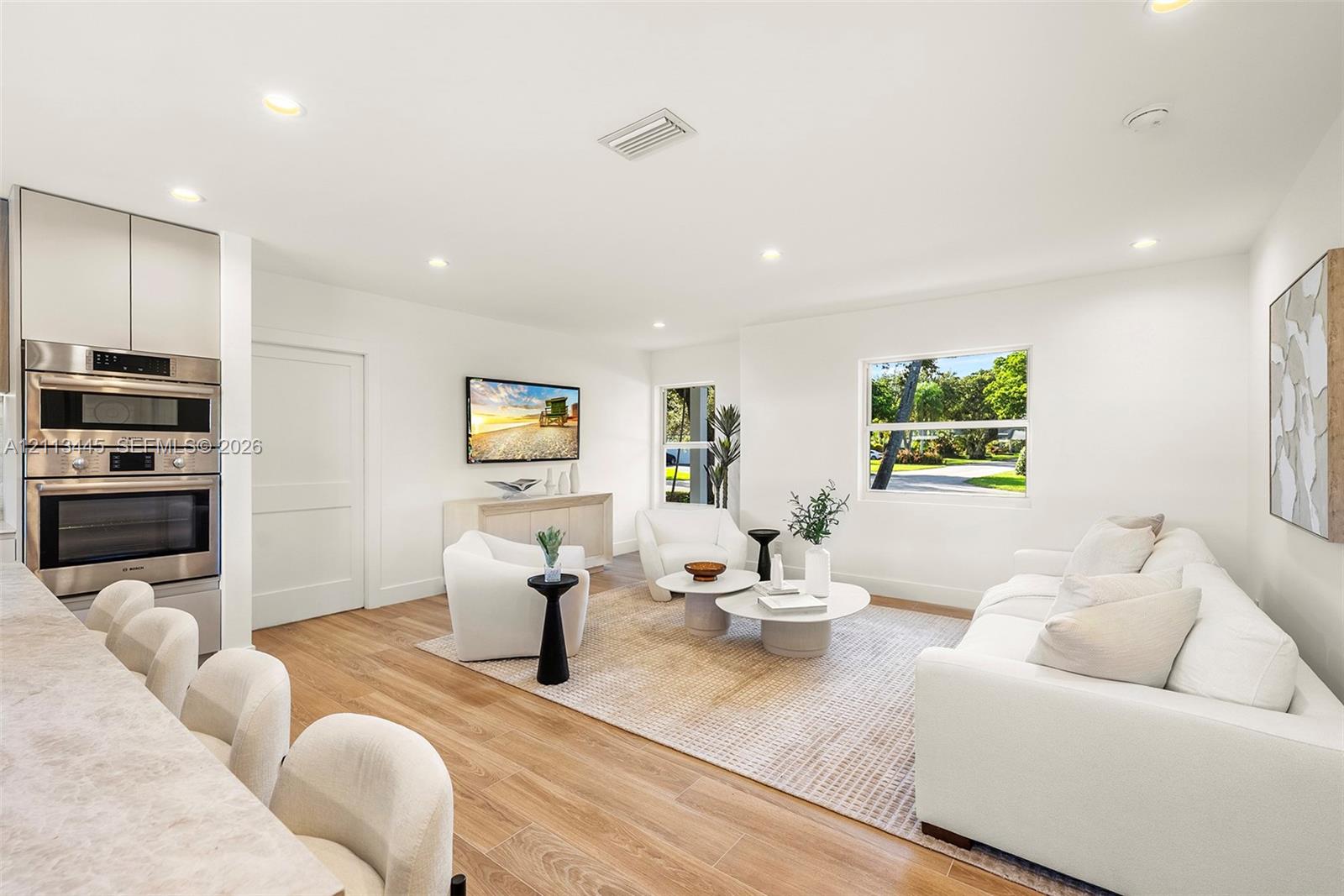 Living area featuring wood-finish flooring, recessed lighting, and integrated stainless steel double wall ovens