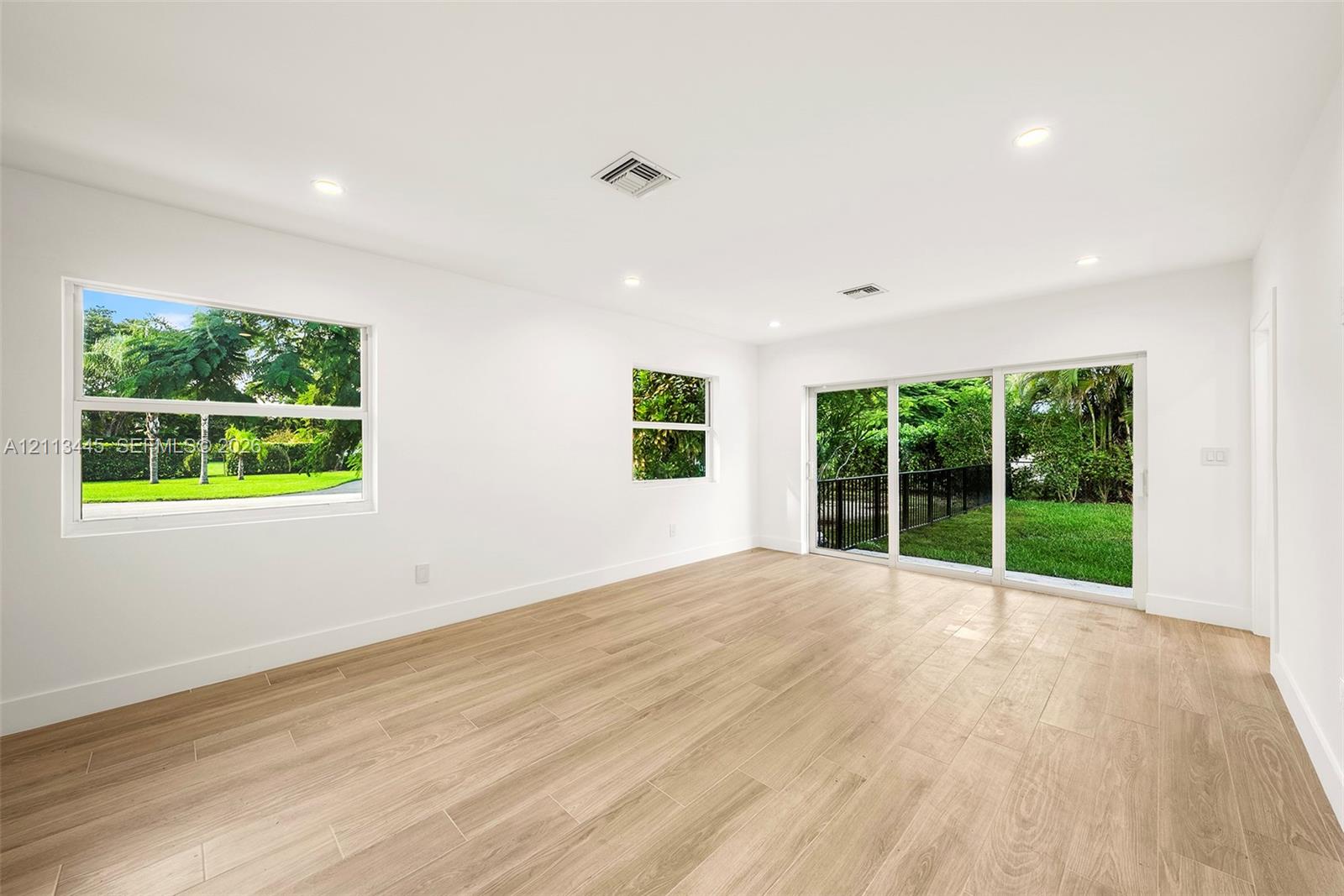 Neutral interior space featuring wood-finish flooring, recessed lighting, and large windows