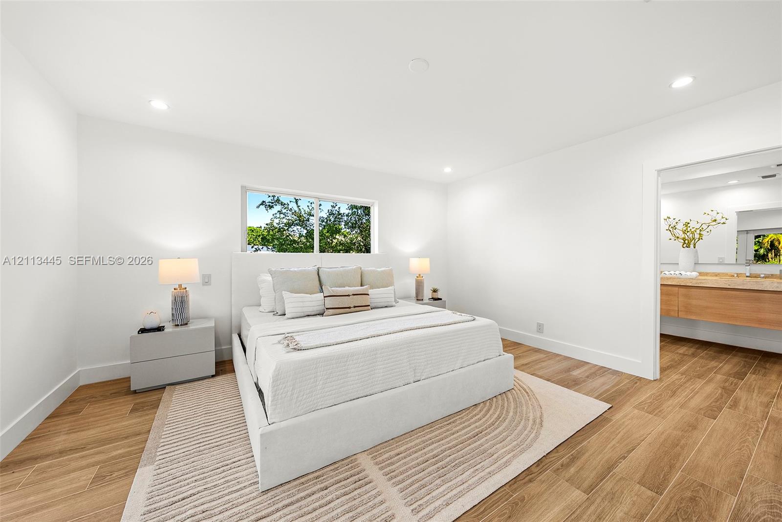 Bedroom featuring recessed lighting, wood-finish flooring, and a window with exterior greenery