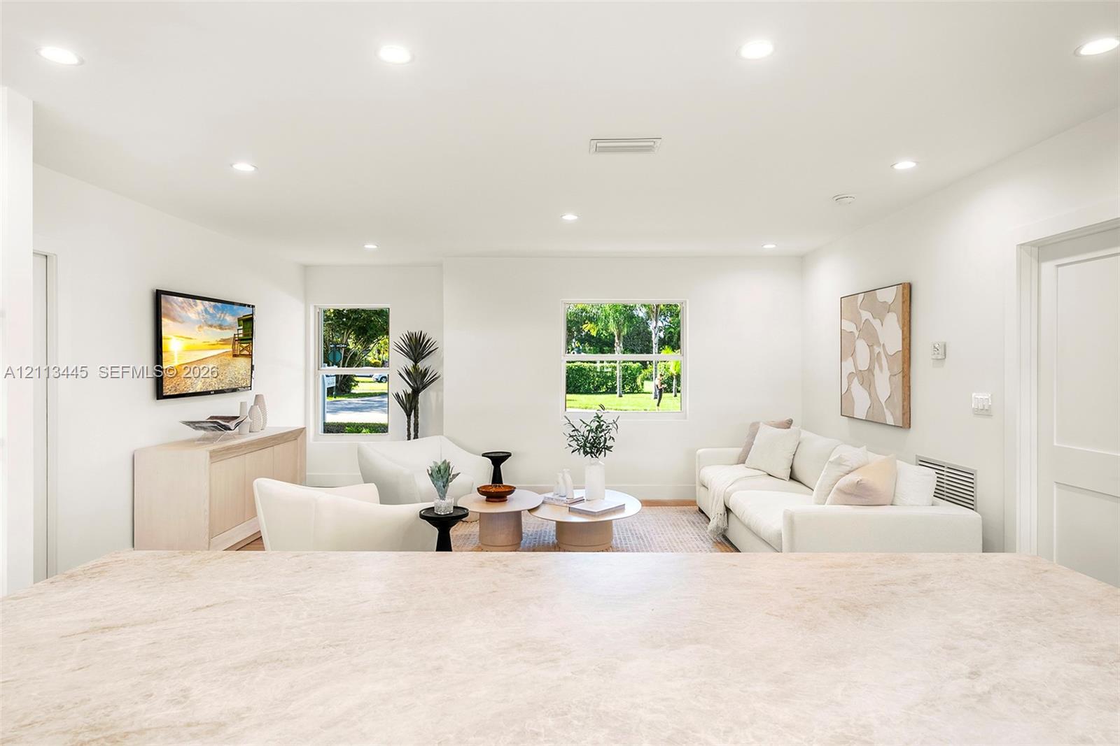 Neutral-toned countertop with integrated breakfast bar, recessed lighting, and dual windows
