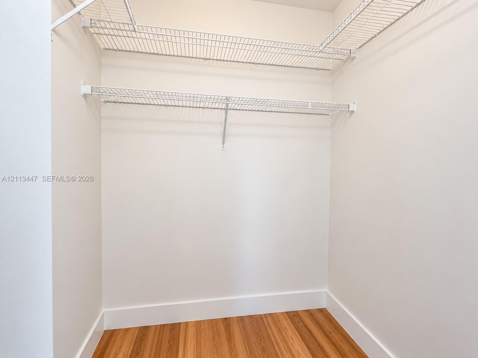 Walk-in closet featuring tiered white wire shelving and luxury laminate flooring