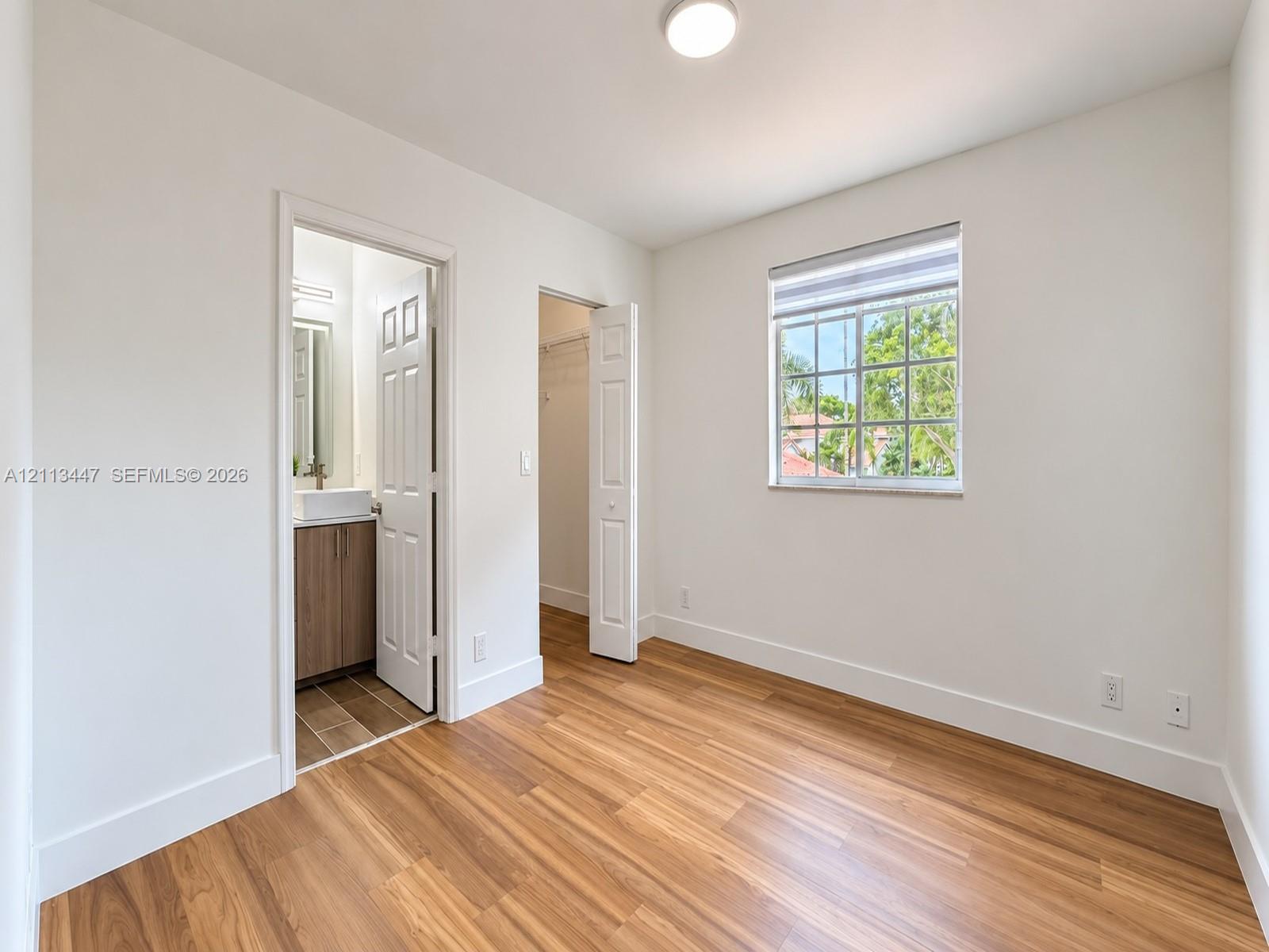 Room with luxury laminated flooring, recessed lighting, grid-pattern window, and two doors providing interior access