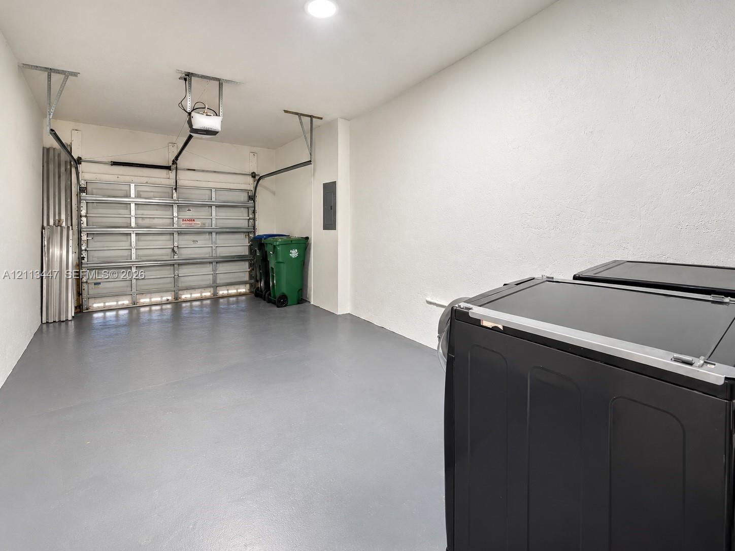 Garage space featuring a painted concrete floor, recessed ceiling lighting, and a metal sectional garage door with an automatic opener