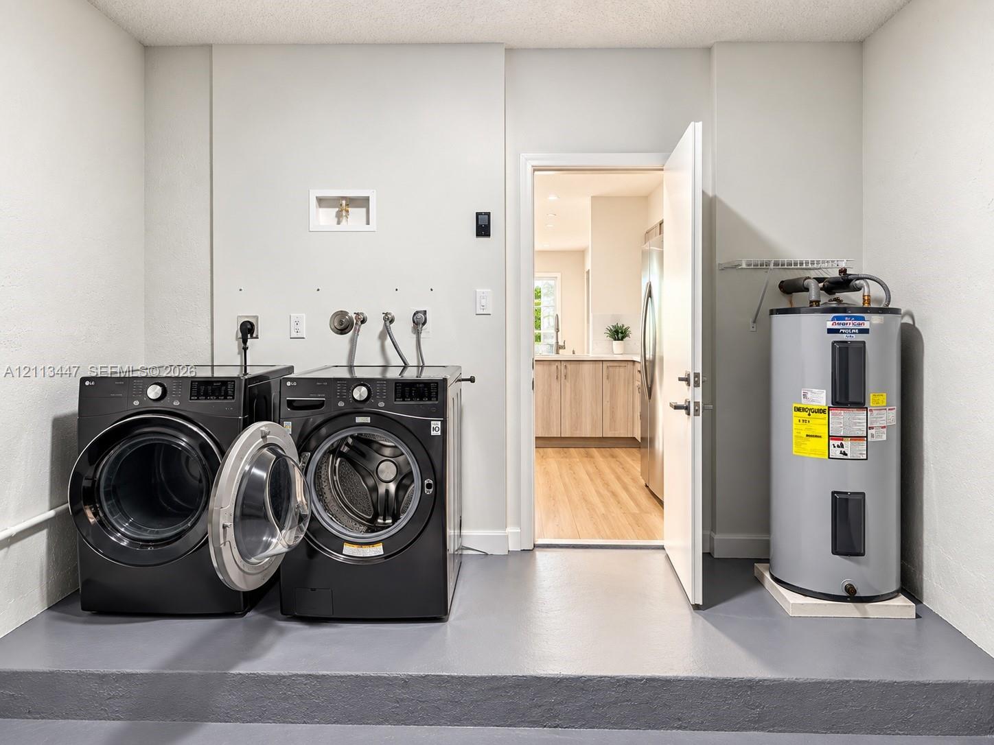 Dedicated utility area featuring a painted concrete floor, dedicated laundry hookups, and an electric water heater