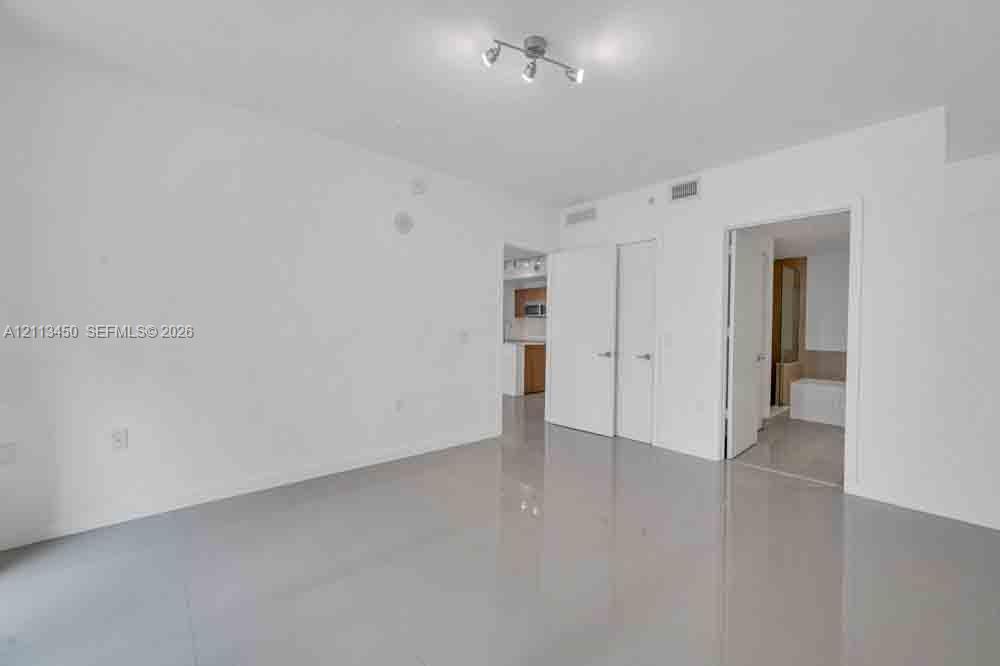 Neutral-toned polished tile flooring, multi-directional track lighting, and solid core interior doors