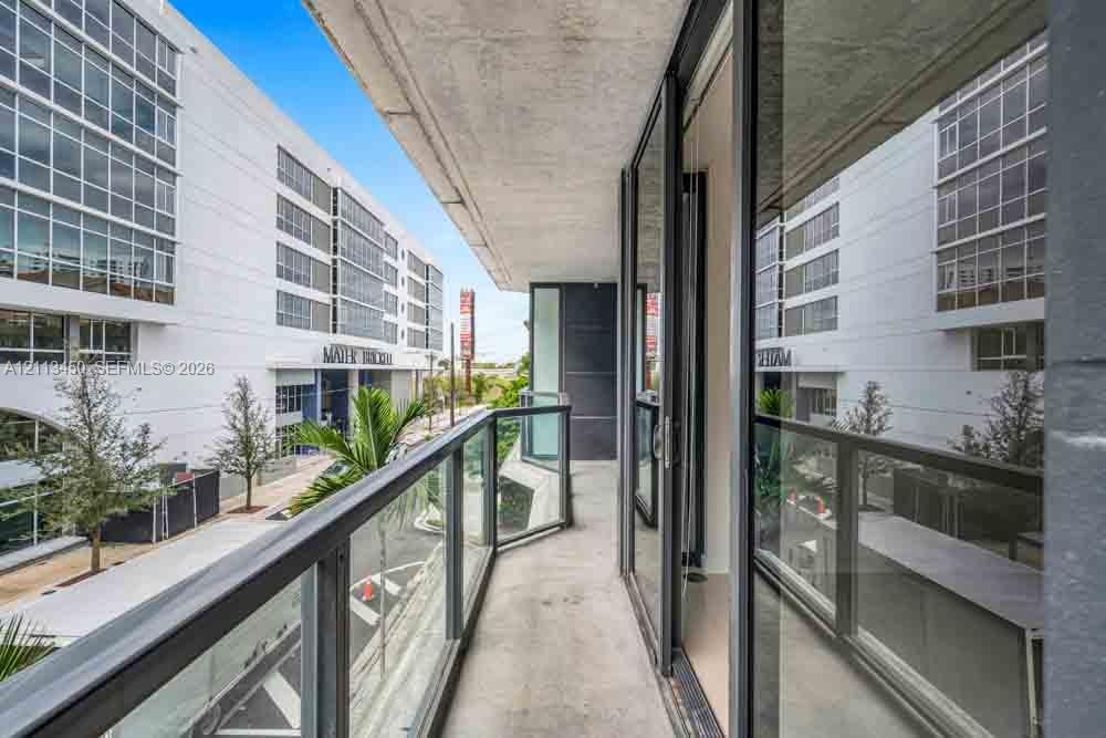 Private balcony featuring concrete flooring and a tempered glass railing with a dark metal frame