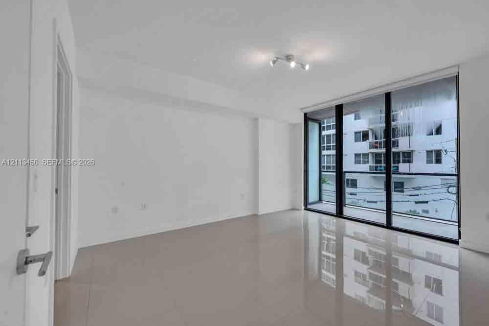 Floor-to-ceiling glass windows, polished tile flooring, and multi-light directional ceiling fixture