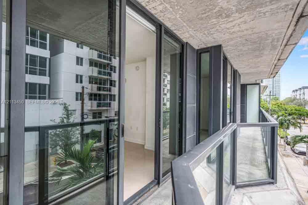Private balcony featuring concrete flooring, a glass panel railing with a dark metal frame, and sliding glass door access