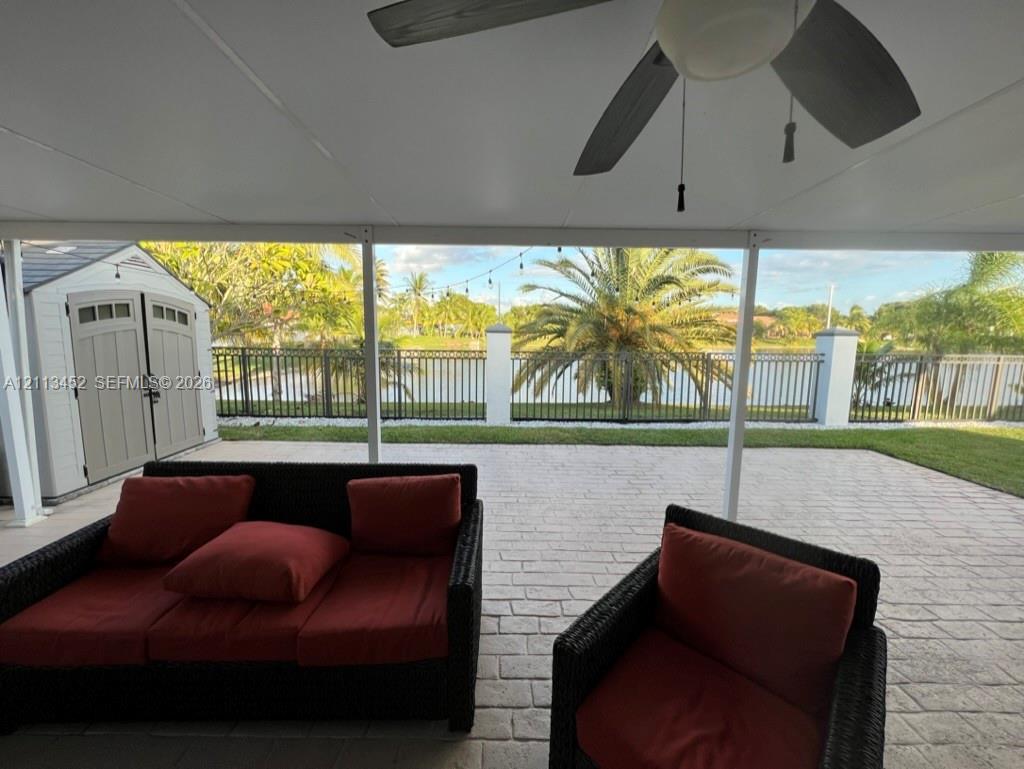 Covered patio featuring a paver surface, ceiling fan, and metal perimeter fencing