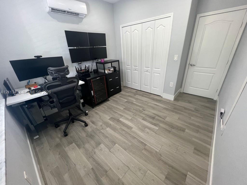 Wood-finish flooring, wall-mounted ductless air conditioning unit, bi-fold closet doors, and interior arched-panel door