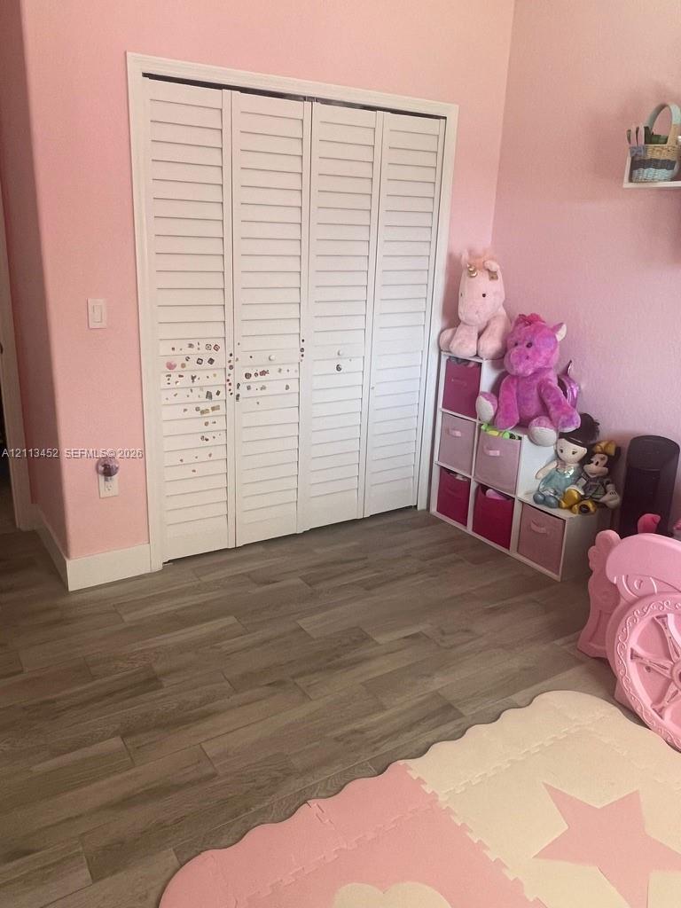 Bi-fold closet doors featuring white louvered panels and wood-finish flooring