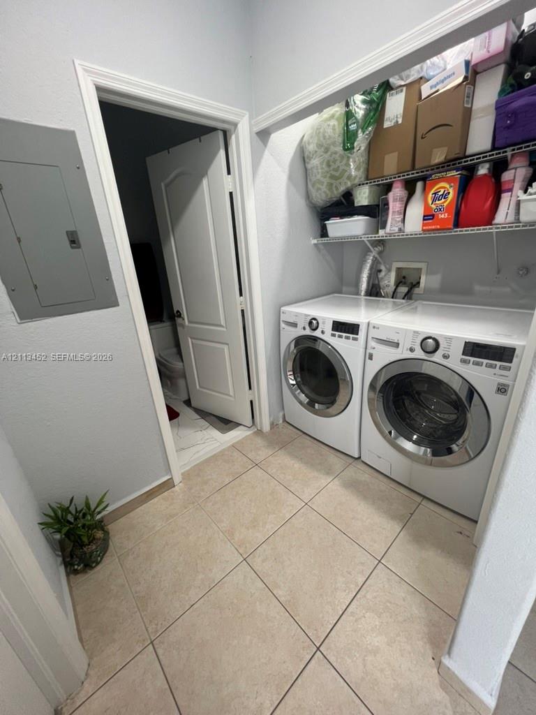 Laundry area featuring large-format tile flooring, built-in wire shelving, and an integrated electrical service panel