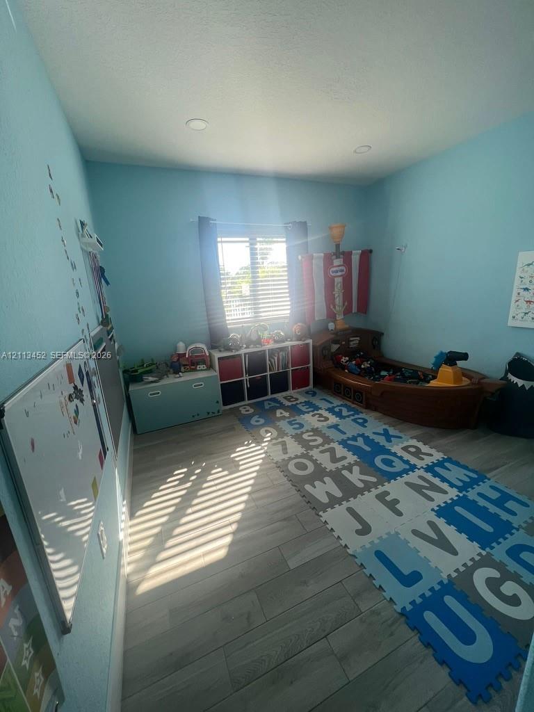 Interior space featuring wood-finish flooring, recessed lighting, and a window with horizontal blinds