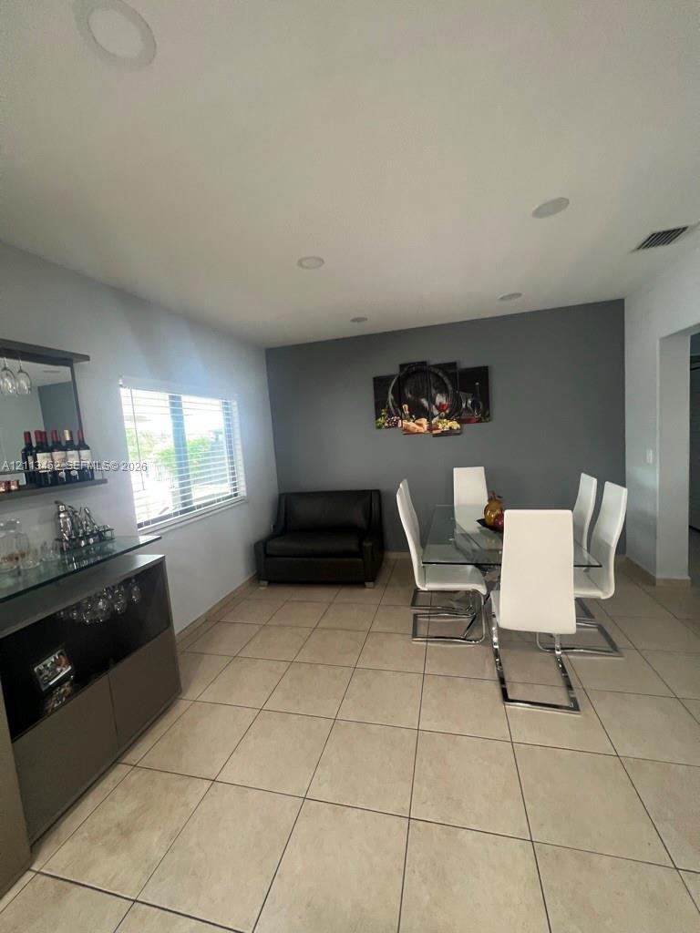 Ceramic tile flooring, built-in recessed lighting, and a neutral color palette featuring a dark gray accent wall