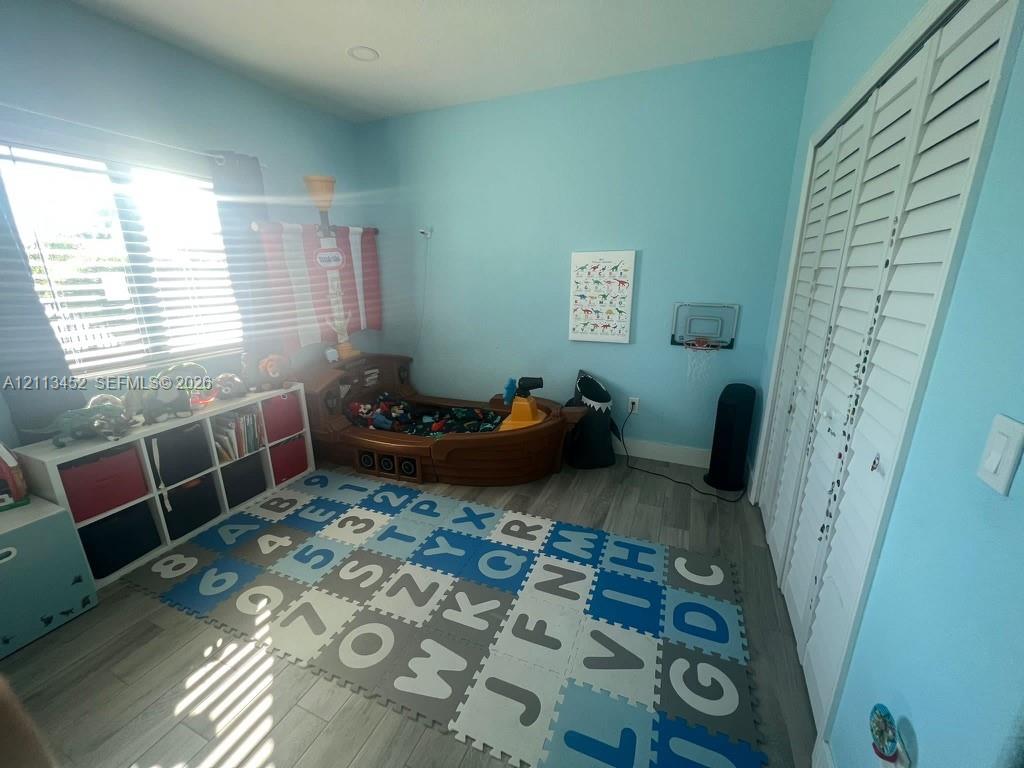 Bedroom featuring wood-finish flooring, recessed lighting, and white louvered-style closet doors