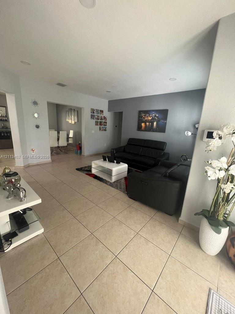 Open-concept interior featuring neutral ceramic tile flooring, recessed lighting, and a charcoal-toned accent wall